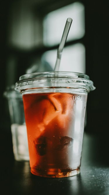 selective focus photo of clear disposable cup with red liquid